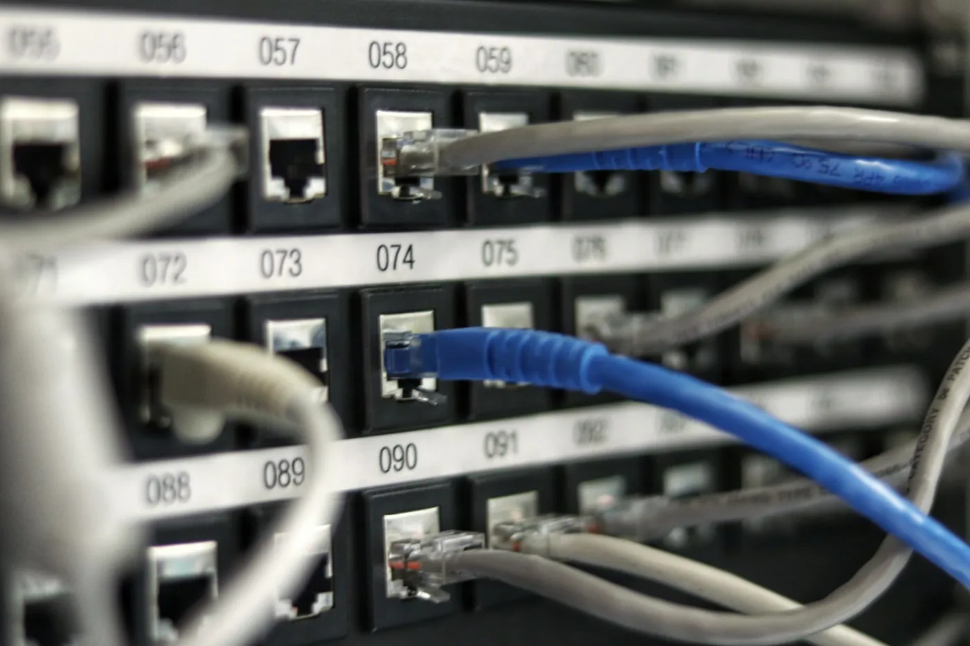 Baie de brassage réseau avec câbles Ethernet et un câble bleu au premier plan